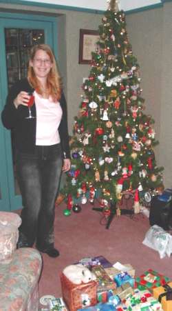 Heather stands by her mum's xmas tree with a large pile of her presents